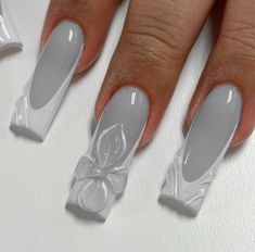 a woman's hand with white nail polish and bows on the tip of her nails