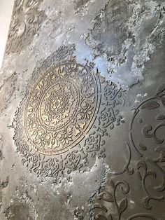 an intricate design on the side of a metal wall paneled in silver and gold