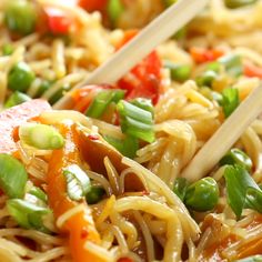 two chopsticks sticking out of noodles with vegetables