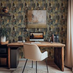 a desk with a computer on it in front of a wallpapered background and a painting