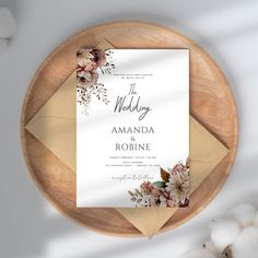 a wedding card with flowers on it sitting on top of a wooden plate next to cotton