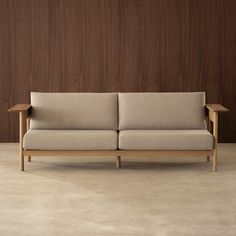 a couch sitting on top of a cement floor next to a wooden wall with wood trim