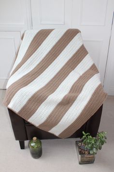 a brown and white blanket sitting on top of a chair next to a potted plant