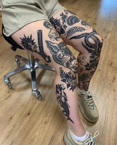 a person sitting on a chair with tattoos on their legs