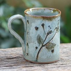 a ceramic mug with flowers painted on the outside and inside is sitting on a wooden table