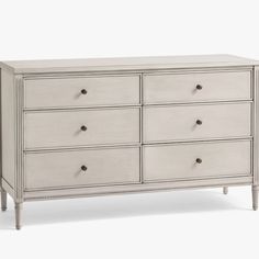 a white dresser with six drawers and two pulls on the top, in front of a white background