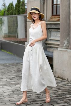 "This white linen midi skirt is perfect for adding a touch of vintage charm to your wardrobe! Featuring a row of buttons down the front and a flattering A-line silhouette, this skirt is both stylish and comfortable. Made from high-quality linen, it's perfect for keeping cool on warm days. Pair with a white blouse or a denim jacket for a chic and versatile look. DETAIL * 100% Linen * Two pockets * Back elastic waist * Button down skirt * Button front skirt * Below Knee Length * A Line skirt, Midi Summer A-line Skirt With Button Closure, Spring Buttoned Maxi Skirt, Buttoned Maxi Skirt For Spring, Elegant White Linen Skirt, Spring Maxi Skirt With Buttons, Knee-length Summer Skirt With Button Closure, Summer Knee-length Skirt With Button Closure, Chic White Linen Skirt, Chic Spring Maxi Skirt With Buttons