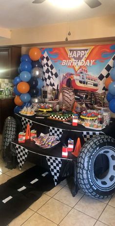 a birthday party with cars and balloons on the floor, including a monster truck cake table