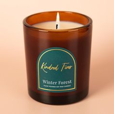 a candle with a label on it sitting in front of a pink background that says winter forest