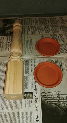 two orange plates and a wooden spatula on top of newspaper