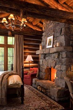 a bedroom with a stone fireplace and bed in it's centerpiece, surrounded by wood paneled walls