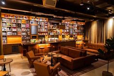 a room with couches, tables and chairs in front of a book shelf filled with books