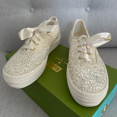 a pair of white tennis shoes with bows on them sitting on top of a green box