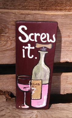 a sign that says screw it and has a wine glass next to it on a wooden surface