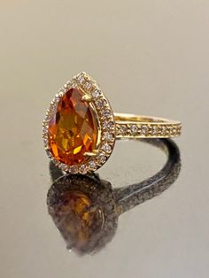 an orange and white diamond ring sitting on top of a reflective surface