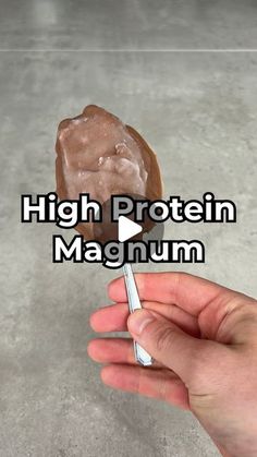 a hand holding a chocolate covered doughnut with the words high protein magnanum on it