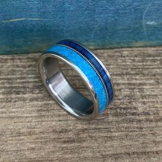 a ring with blue and silver inlays sitting on top of a wooden table