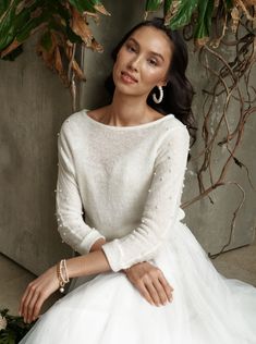 a woman sitting on the ground wearing a white dress