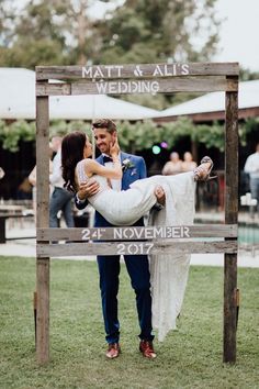 a newly married couple standing in front of a wooden sign