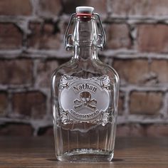 a glass bottle sitting on top of a wooden table next to a brick wall in the background