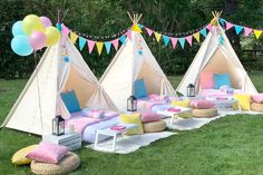 a group of teepee tents sitting on top of a lush green field