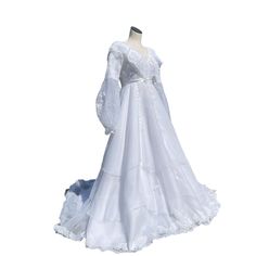 a white wedding gown with long sleeves and ruffles on the skirt is displayed in front of a mannequin