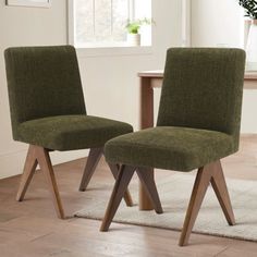 two green chairs sitting next to each other on a wooden floor in front of a window