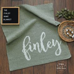 a knitted blanket with the word fancy on it next to a small bowl and candle