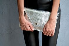 "Silver Symmetria Clutch. The perfect bag for all occasions! Ideal for cocktail and parties or for business meetings depending the size you choose. You can use it as a chic briefcase for your work or as a modern large clutch for a night out. This adorable clutch is handmade out of a genuine, lux Italian silver cow leather. -Small size fits all your essentials, wallet, keys, mobile, cosmetics etc. -Large size fits a 15\" laptop, ipad, portofolio etc and it's perfect as a file folder or as modern Leather Clutch Evening Bag For Night Out, Designer Leather Evening Bag For Party, Designer Leather Clutch For Party, Modern Leather Clutch For Night Out, Elegant Silver Leather Clutch, Leather Pouch Clutch For Parties, Silver Leather Clutch Evening Bag, Silver Chic Clutch As A Gift, Silver Chic Clutch For Gift