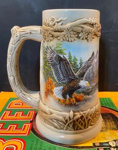 a beer mug with an eagle painted on the front and sides sitting on a table