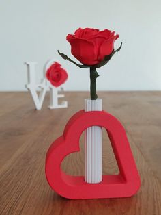 a red rose in a white vase with the word love spelled out next to it