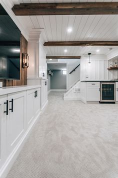 an empty kitchen with white cabinets and wood beams on the ceiling is seen in this image