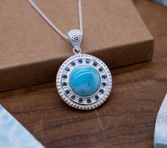 "Emanate the radiant beauty of the ocean with our Ocean's Radiance Silver Pendant. Crafted by Gemoholic Jewelry, this stunning piece showcases a large circle Larimar stone at the heart, encircled by 16 Blue Topaz stones meticulously arranged in a perfect circle. This pendant captures the timeless allure of the sea with an elegant and captivating design. Product Details: Pendant Material: 925 Sterling Silver Gemstones: Large Circle Larimar, 16 Blue Topaz Chain: 18 Inch About Gemoholic Jewelry: At Gemoholic, we are dedicated to creating jewelry that celebrates the beauty of gemstones and the elegance of design. Each piece is a unique work of art, capturing the serenity and captivating qualities of the ocean.  Here's what makes this pendant special: - Captivating Design: This pendant exudes c Handmade Aquamarine Round Jewelry, Larimar Gemstone Pendant Necklace, Larimar Gemstone Pendant Necklaces, Turquoise Aquamarine Round Necklace, Turquoise Aquamarine Necklace, Round Turquoise Aquamarine Necklace, Spiritual Round Blue Topaz Jewelry, Spiritual Round Larimar Jewelry, Handmade Larimar Round Necklace