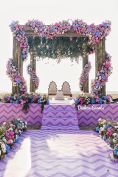 an outdoor ceremony with purple and pink flowers on the altar, chevron table cloth