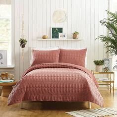 a bed in a bedroom with pink comforter and pillows on top of the bed