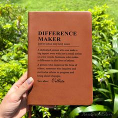 someone is holding up a book in front of some bushes and trees with the words,'difference maker'written on it