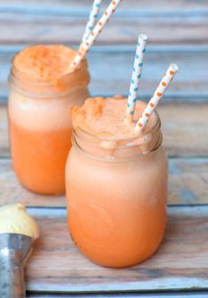 two mason jars filled with orange juice and topped with straws