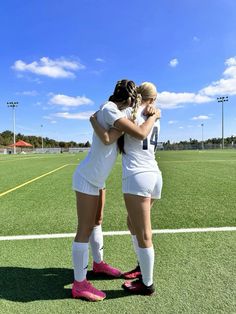 two female soccer players hugging each other on the field