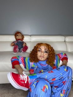 a woman with red hair and makeup is sitting on the floor next to a couch