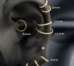 an ear with three rows of gold and diamonds on it, in front of a black background