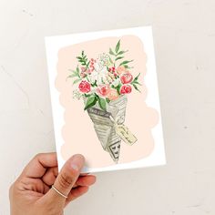 a person holding up a card with flowers in it