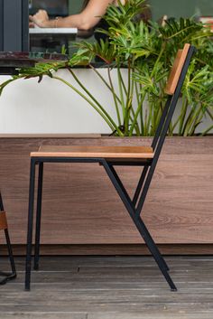 a wooden chair sitting in front of a window next to a planter filled with potted plants