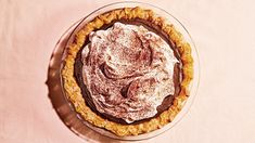 a chocolate pie with powdered sugar on top sits on a pink tablecloth and is ready to be eaten