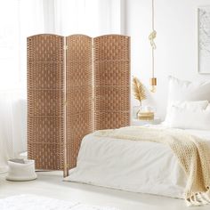 a room divider made out of wicker with white sheets and pillows on the floor