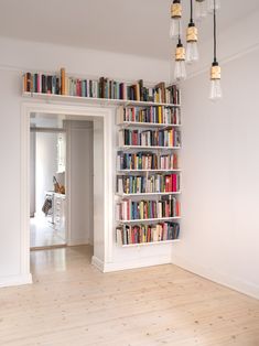 a book shelf filled with lots of books on top of a hard wood floor next to a doorway