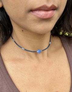 a close up of a woman wearing a necklace with blue beads on her neck and chest