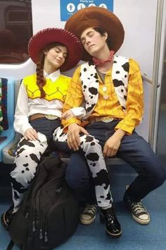 two people dressed in costumes sitting on a subway train together, one wearing a cowboy hat and the other as a cowgirl