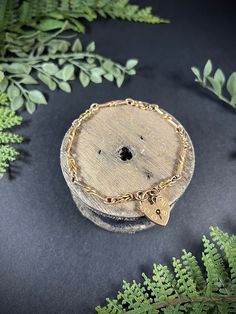 a piece of wood with a heart charm on it sitting next to some plants and leaves