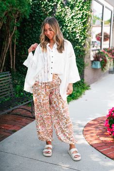 The Lakelyn Lace Ivory Button Up Top is a beautifully crafted, off-white lace and gauze blouse that exudes a romantic, bohemian vibe. The top features a delicate mix of lace and textured fabric, creating a soft and airy look perfect for layering. It has a button-down front with small, dark buttons that add a subtle contrast to the light fabric. The collar is slightly frayed, contributing to its relaxed and effortless style. The sleeves are voluminous and made entirely of intricate lace, adding a Bohemian Blouse With Lace Patchwork For Vacation, Bohemian Button-up Blouse For Vacation, Spring Bohemian Crochet Top With Floral Embroidery, Bohemian Blouse With Lace Sleeves, Bohemian Crochet Top With Floral Embroidery For Spring, White Bohemian Crochet Top For Day Out, Bohemian Cream Crochet Top For Day Out, Bohemian Lace Top With Floral Print, Bohemian Lace Blouse For Vacation