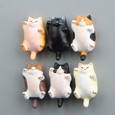 five different colored cat figurines sitting on top of a gray surface with white and black cats